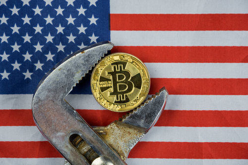 A wrench clamps a gold Bitcoin with the U.S. flag, symbolizing cryptocurrency regulation and platforms like Coinmama.