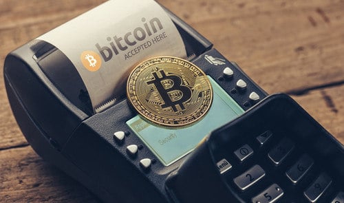 A Bitcoin coin on a POS terminal reads "BTC ACCEPTED HERE," signifying Bitcoin payment acceptance. Buy crypto on Coinmama.