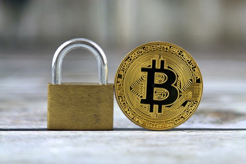 A brass padlock beside a Bitcoin coin symbolizes security when you buy crypto through Coinmama.
